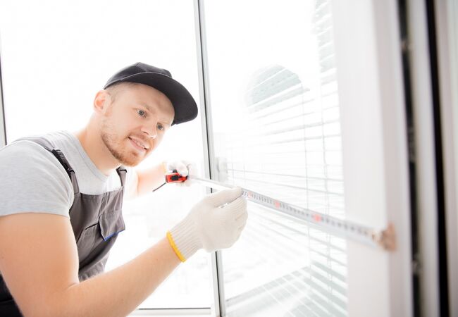 Bild Servicemitarbeiter misst einen Fensterflügel mit dem Maßband aus