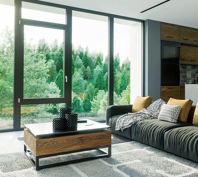 Bild Wohnzimmer mit Aluminium Panoramafenster in dunkler Farbe und Holzzusätze mit moderner Küche hinten und Aussicht auf Wald