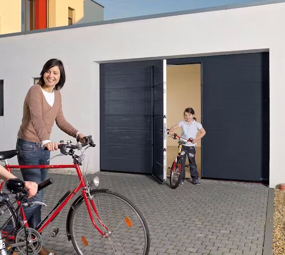 Bild Eine Familie mit Fahrrädern genießt den Tag vor einem modernen Garagentor mit integrierter Tür.