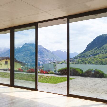 Bild Große Glasfenster bieten einen beeindruckenden Blick auf die Berge und den Garten, ideal für modernen Sonnenschutz.