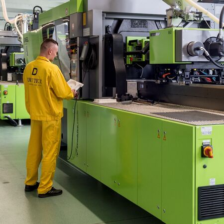 Bild Fabrik Mitarbeiter in Arbeitskleidung bei Fenster- und Türen Hersteller Drutex steht neben Produktionsmaschine