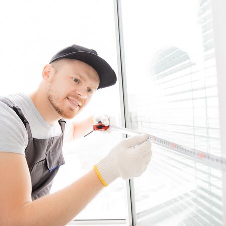 Bild Servicemitarbeiter misst einen Fensterflügel mit dem Maßband aus