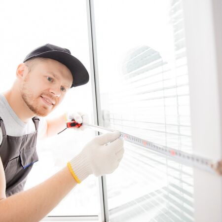 Bild Servicemitarbeiter misst einen Fensterflügel mit dem Maßband aus